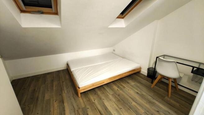 A cozy student's bedroom featuring a single bed...