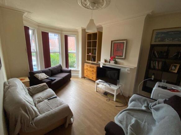 A spacious, well-lit living room featuring larg...