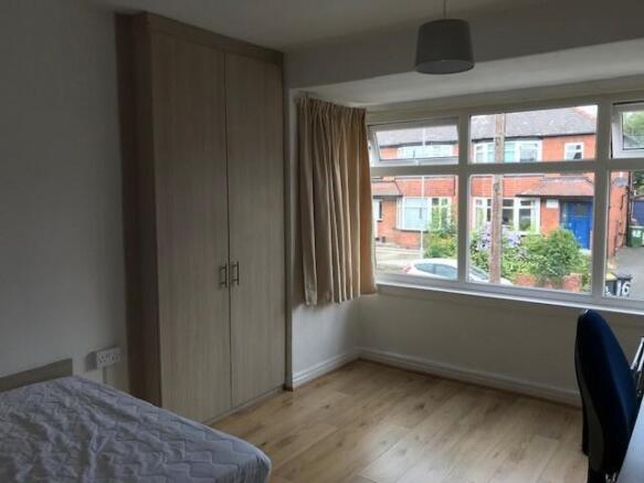 A tidy and well-lit bedroom with a large window...