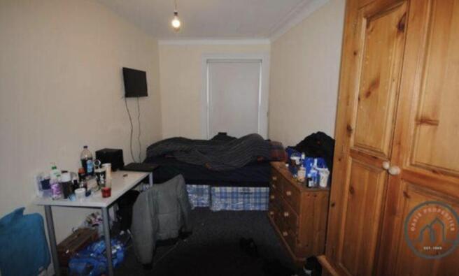 A modest single bedroom featuring a bed with a ...