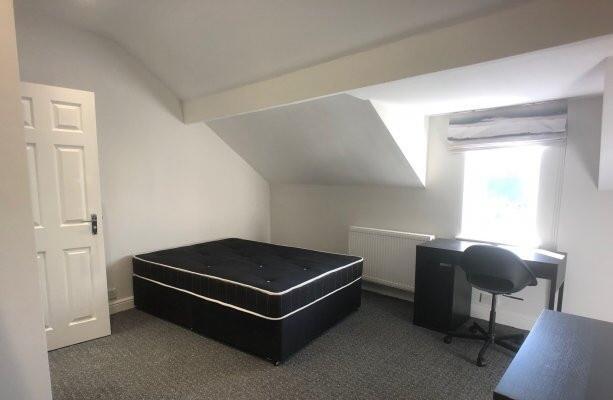 A spacious and well-lit bedroom featuring a lar...