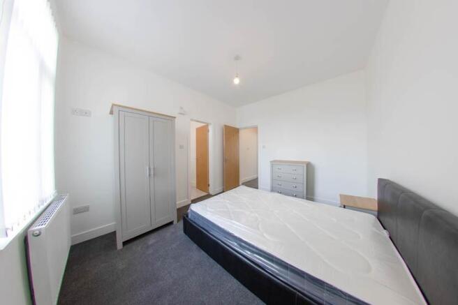 A spacious, well-lit master bedroom featuring a...