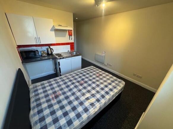 A compact studio apartment featuring a bed with...