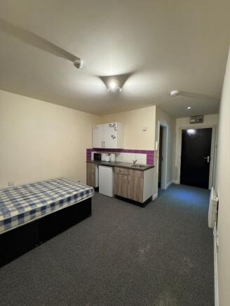 A compact studio apartment featuring a small ki...