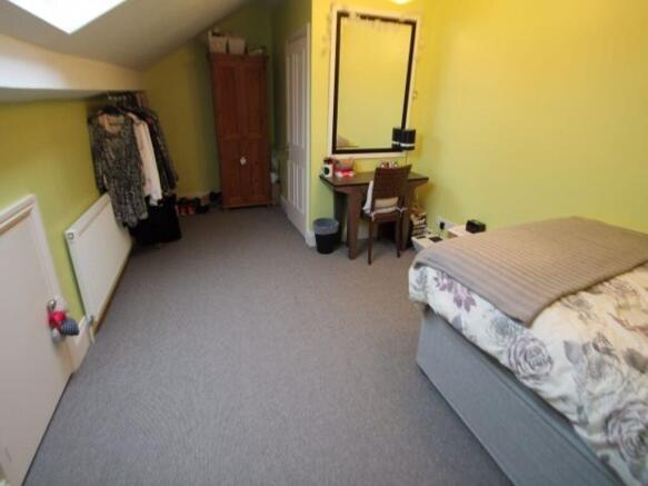 A well-lit, tidy bedroom featuring a comfortabl...