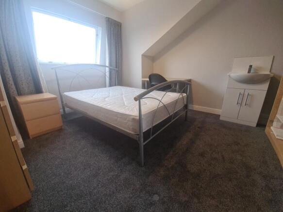 A spacious double bedroom featuring a large bed...