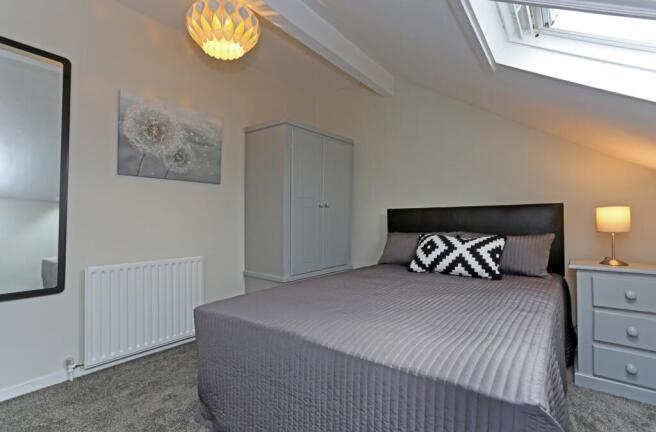 Bright and cozy master bedroom featuring a comf...