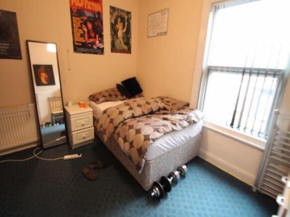 A spacious, well-lit double bedroom with a comf...