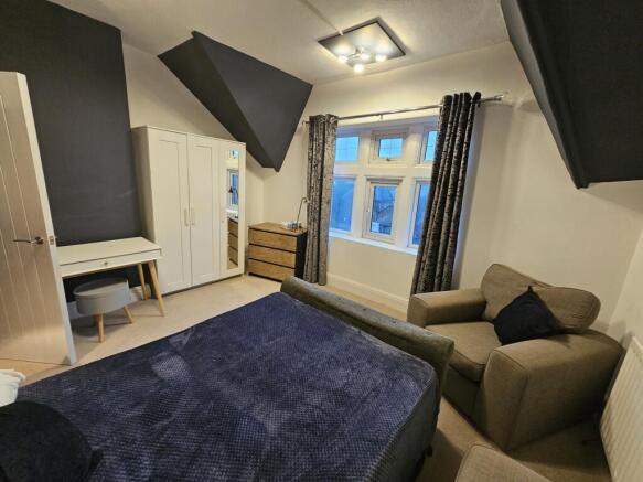 A spacious master bedroom featuring a comfortab...