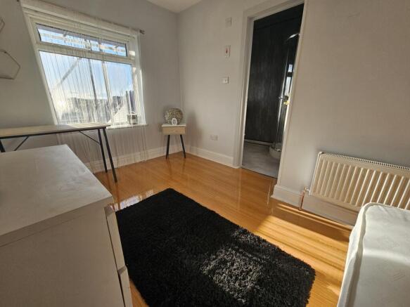 A spacious and well-lit master bedroom with woo...