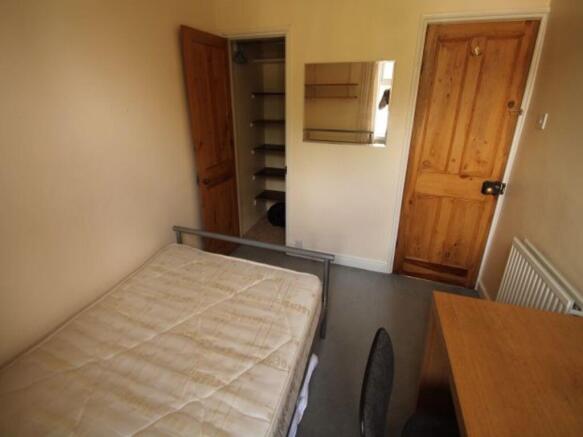 A cozy student bedroom featuring a bed and basi...