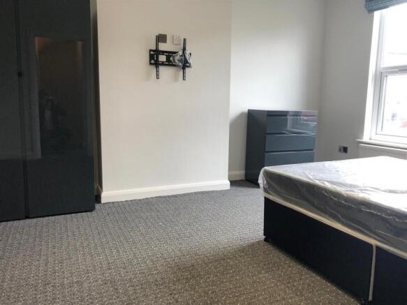 A modest single bedroom featuring a bed, window...