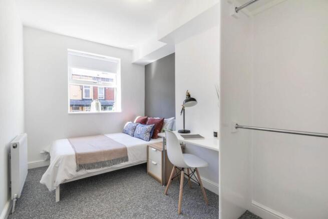 A bright and tidy bedroom featuring a comfortab...