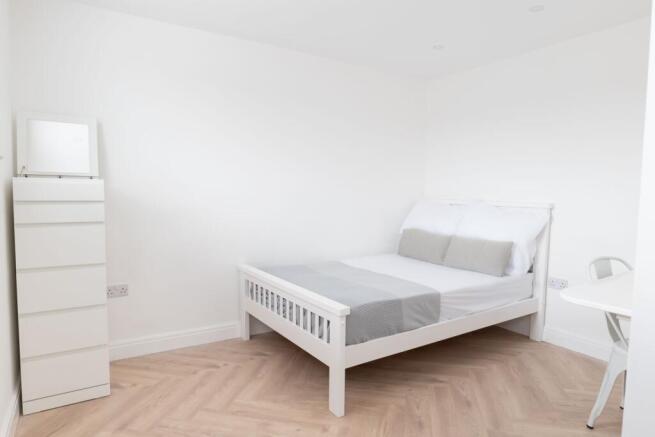 A bright, neatly maintained white bedroom with ...