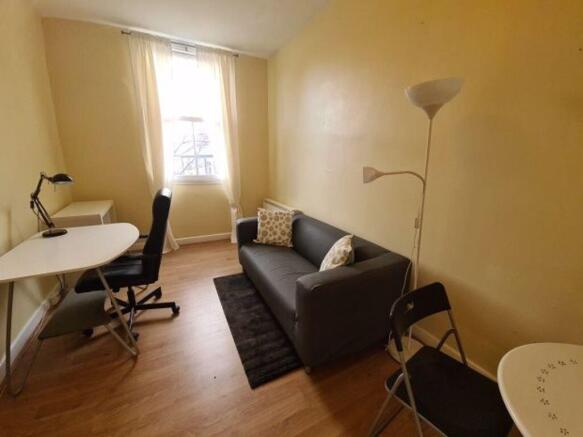 A cozy single bedroom featuring a compact works...