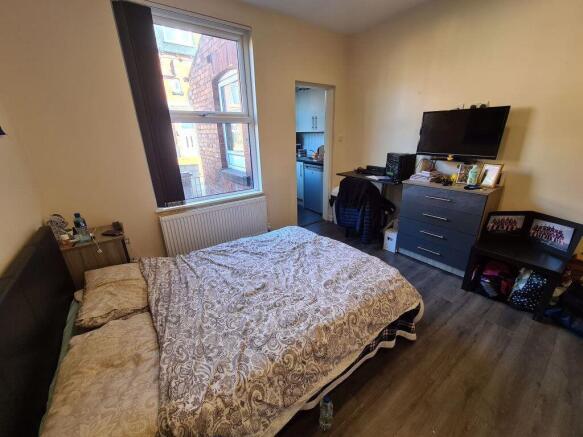 A warmly lit bedroom featuring a comfortable do...