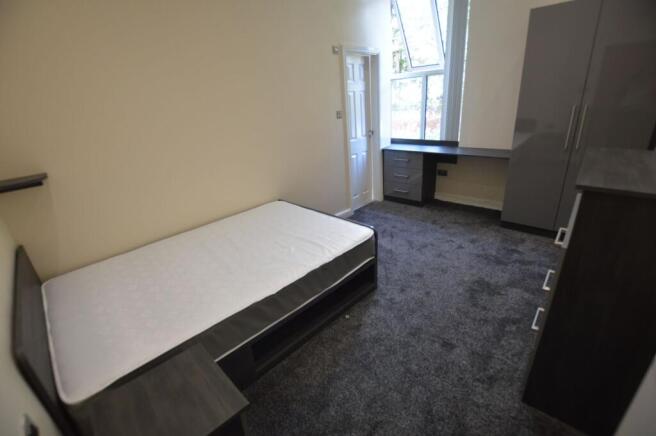 A cozy single bedroom with a comfortable bed an...