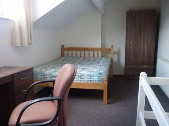 A cozy bedroom featuring a wooden bed frame, a ...