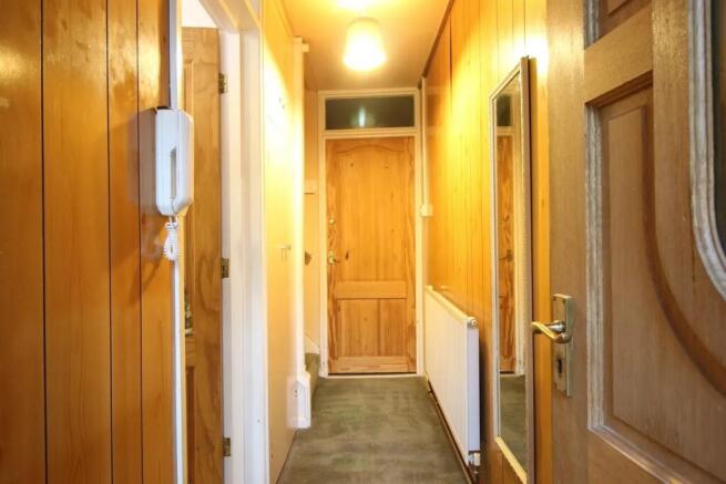 A narrow hallway featuring warm wooden panel wa...