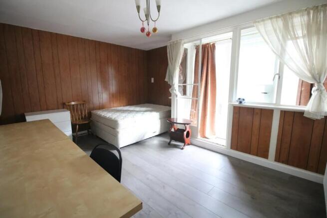 A tidy single bedroom featuring wood-paneled wa...