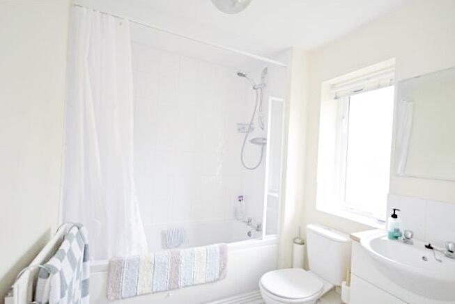 Bright, clean bathroom with a bathtub and overh...