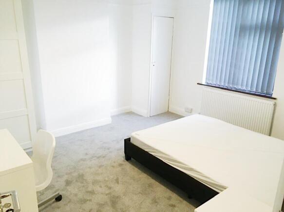 Bright, neutral double bedroom with a simple be...