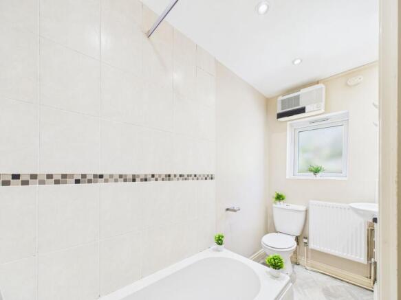 Bright and clean bathroom featuring a bathtub w...