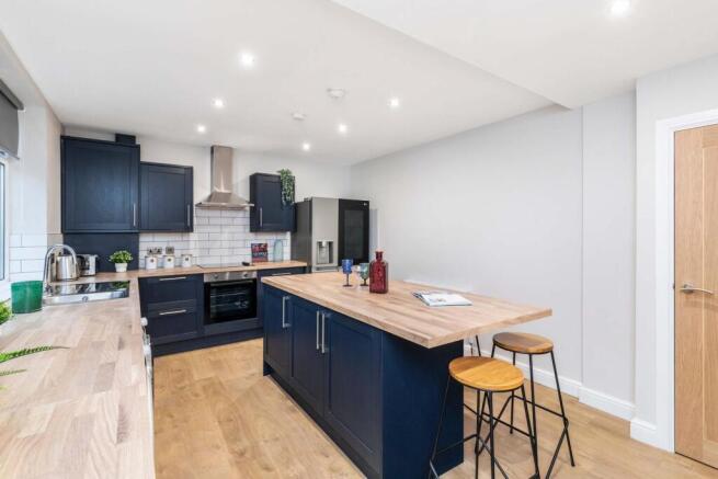 Modern and well-lit kitchen with sleek dark cab...