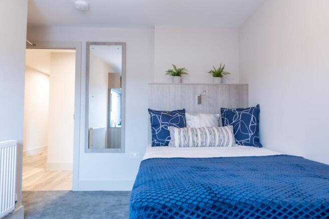 A well-lit, modern bedroom featuring a neatly m...