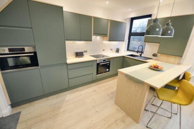 Contemporary fitted kitchen with matte green ca...