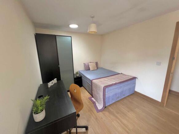 Bright, simply furnished bedroom with a double ...