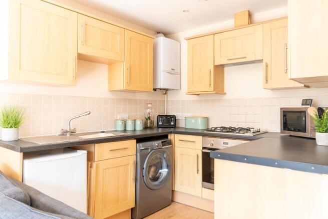 Bright modern kitchen with light wood cabinets,...