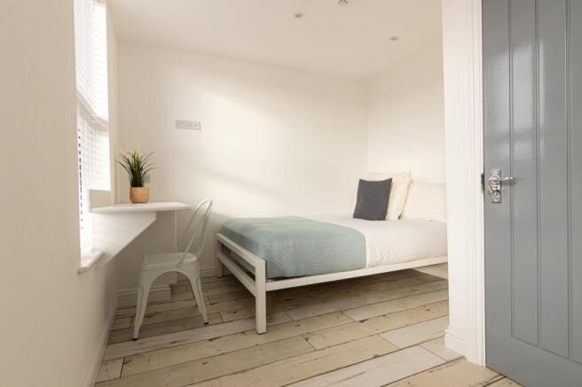 Bright, minimalist bedroom with pale wood floor...