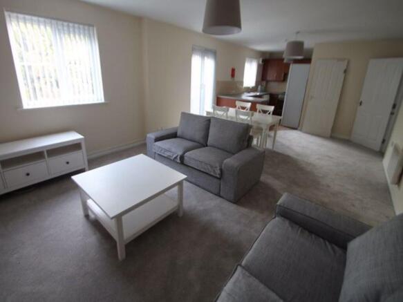 Bright, carpeted living room with matching grey...