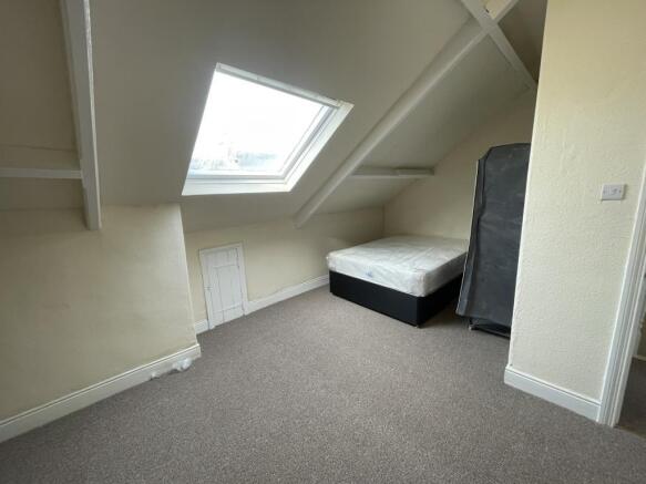 Bright attic bedroom with a sloped ceiling and ...