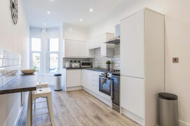 Bright modern kitchen with white cabinetry, int...