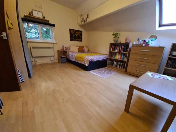 Neat, well-kept bedroom with light wood floors,...