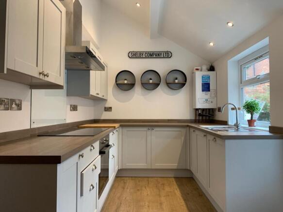 Bright, modern galley kitchen with white cabine...