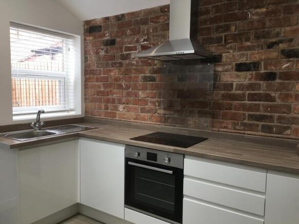 Modern fitted kitchen with white cabinetry, woo...