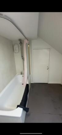 A compact bathroom featuring a bathtub with a s...