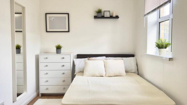 Bright, neatly styled bedroom with a comfortabl...