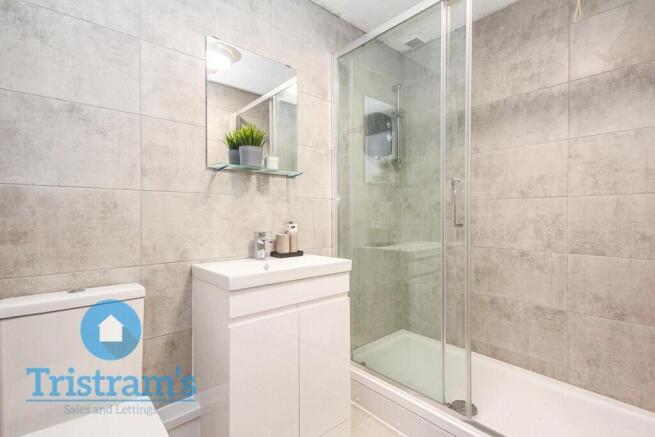 Modern tiled bathroom with a glass-enclosed sho...