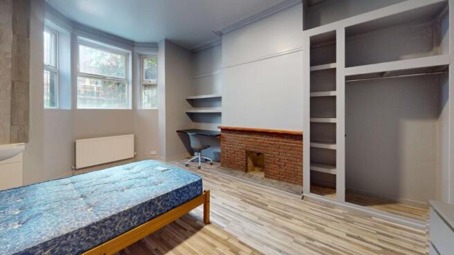 A well-lit bedroom featuring a large window, a ...