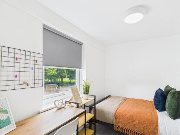 Bright, neatly furnished bedroom with a comfort...