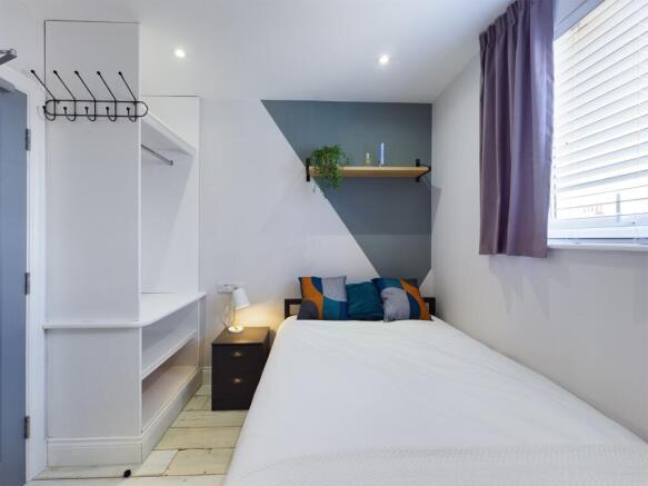 A bright and tidy student bedroom featuring a c...