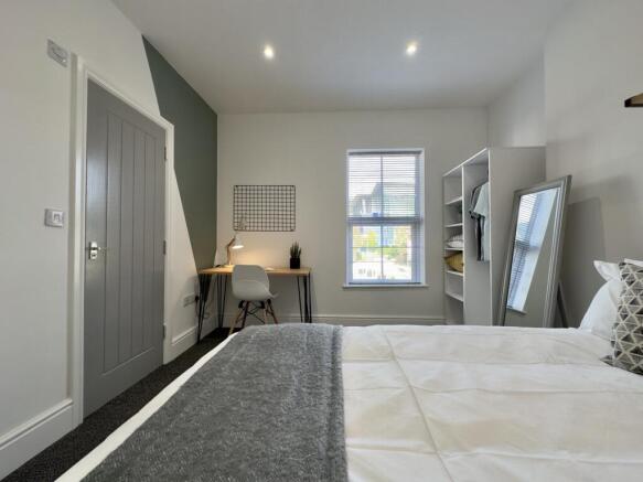 A bright and spacious double bedroom with a coz...