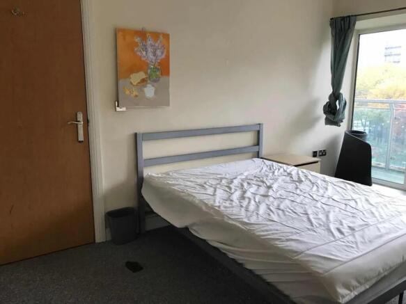 A bright double bedroom featuring a large windo...