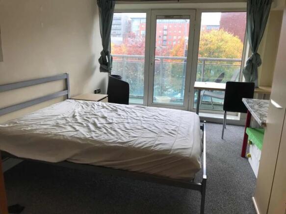 A bright double bedroom featuring a large windo...