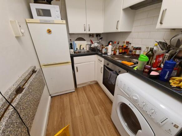 Compact fitted kitchen with white cabinetry, fr...