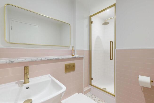 Modern en-suite bathroom with pale pink tiled w...